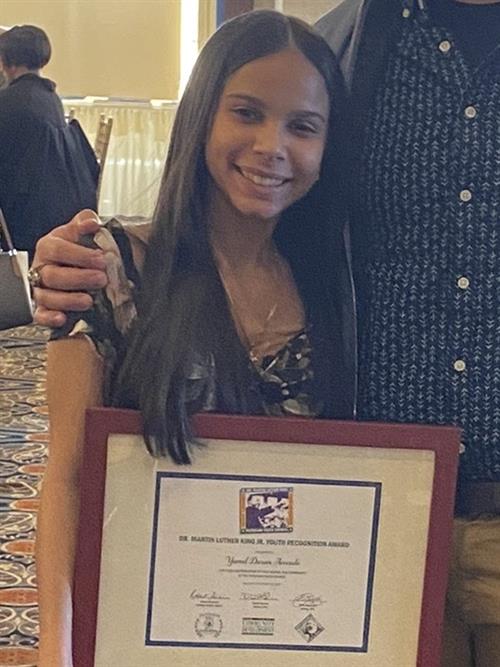 Young female posing with a framed certificate.